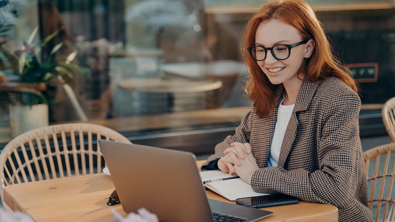 A person sitting at a desk with a laptop reading about QuickBooks Online new features and updates